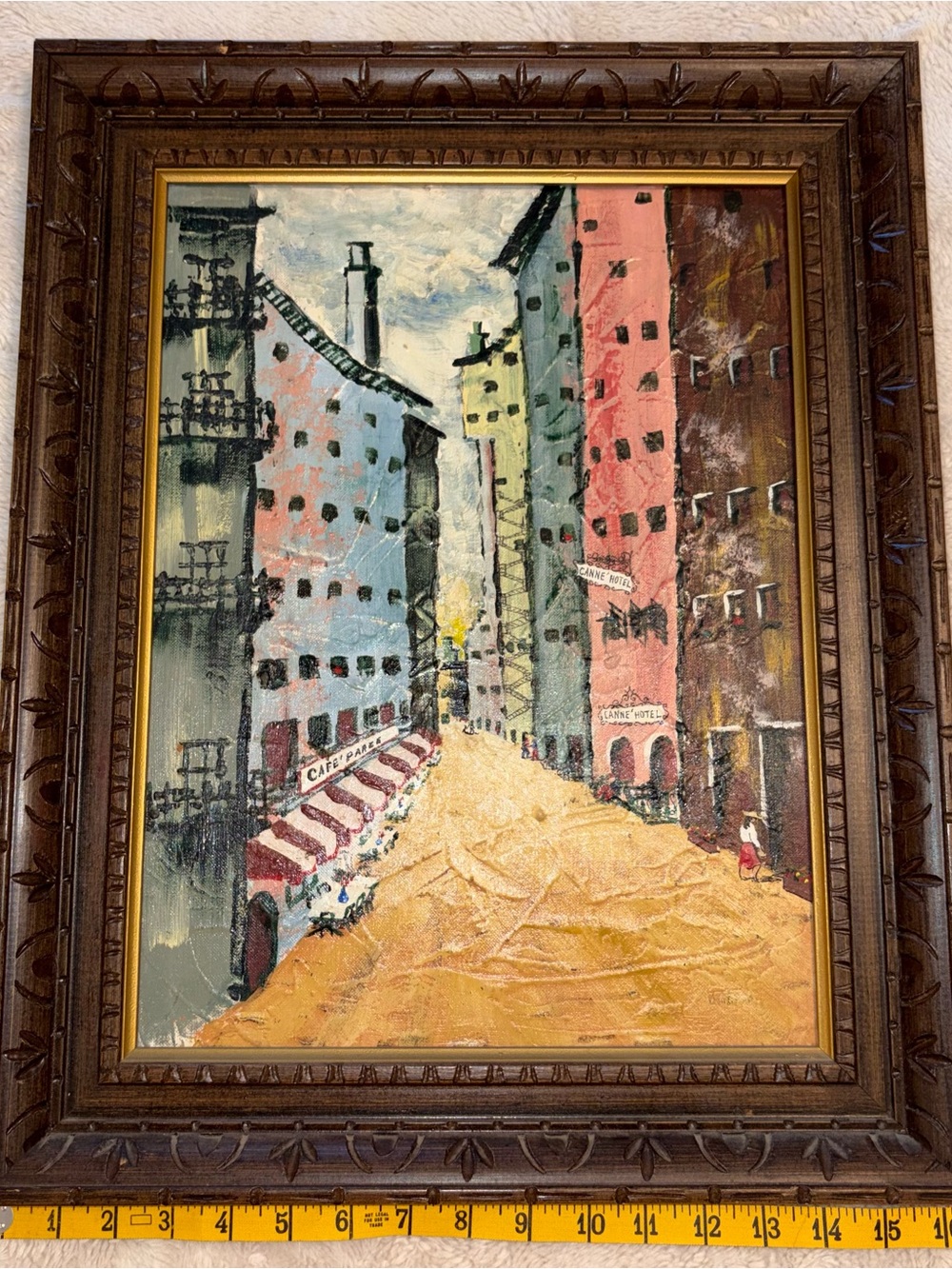 This vintage artwork is an oil-on-canvas painting of a European street scene